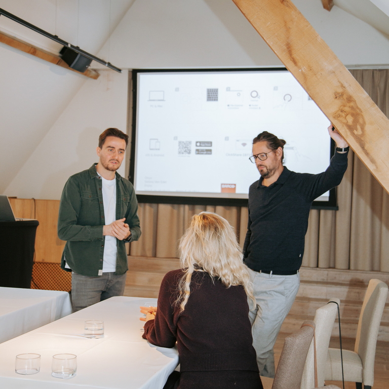 philippe en thijs tijdens de kwartaalmeeting aan het spreken met een zittend persoon