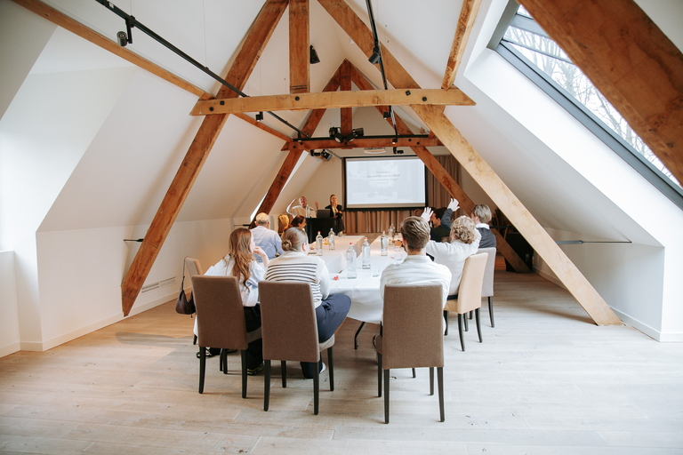 Kwartaalmeeting: alle aanwezigen aan tafel luisterend naar de presentatie.